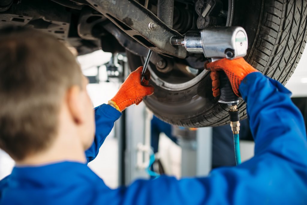 Technician with a wrench repair car suspension Technician with a wrench repair car suspension